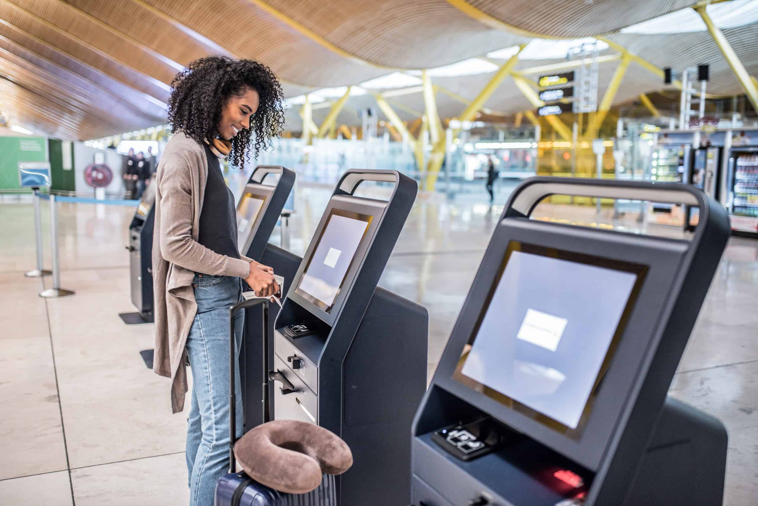 Young woman checking in using a self checkin kiosk at an international airport