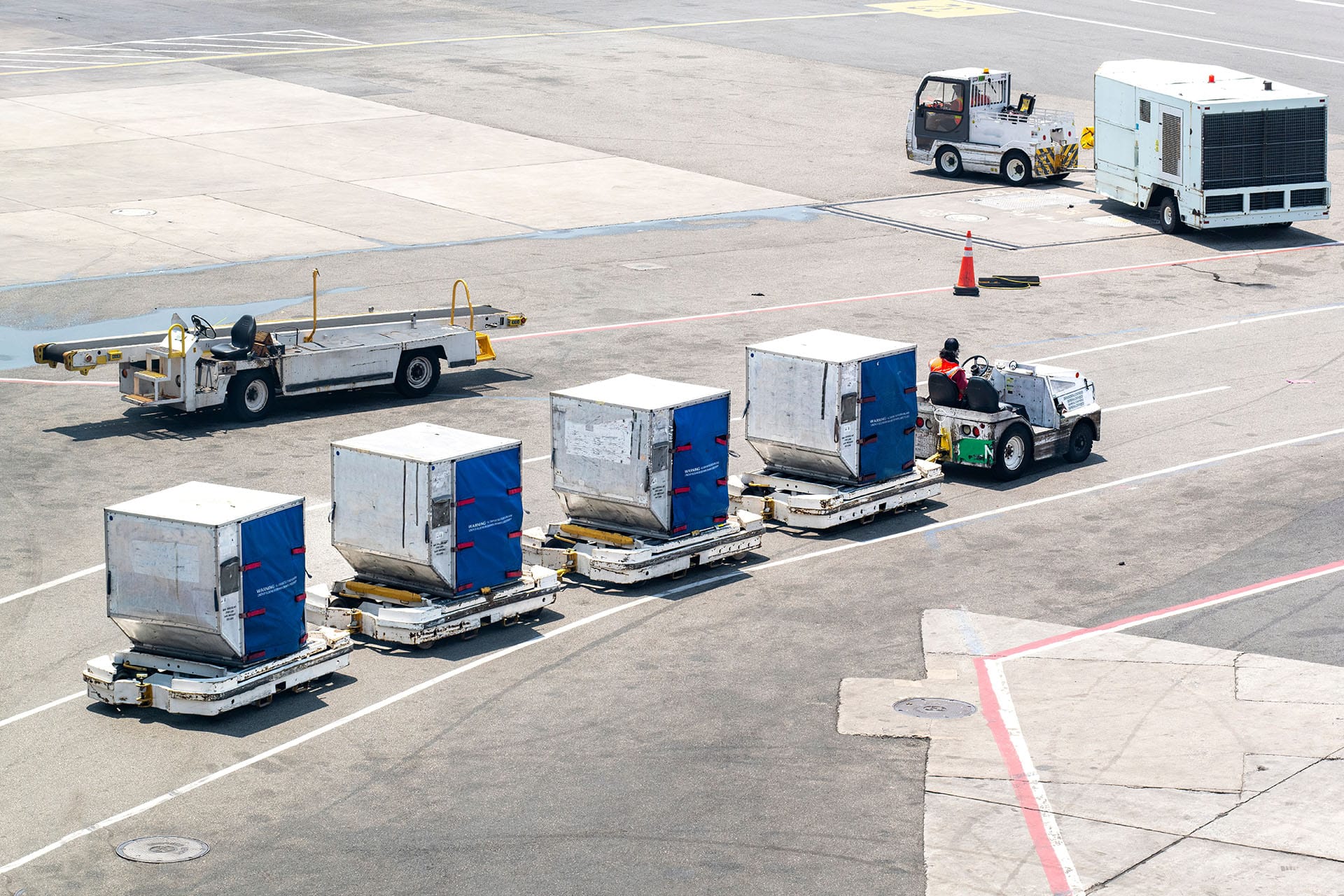 An airport tug pulling containers of inflight meals to an aircraft