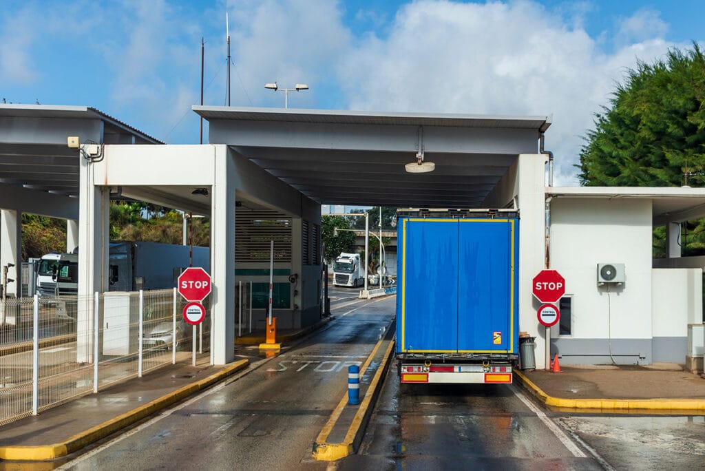 Een beeld van de achterkant van een vrachtwagen die door een douanecontrole een veerboothaven verlaat