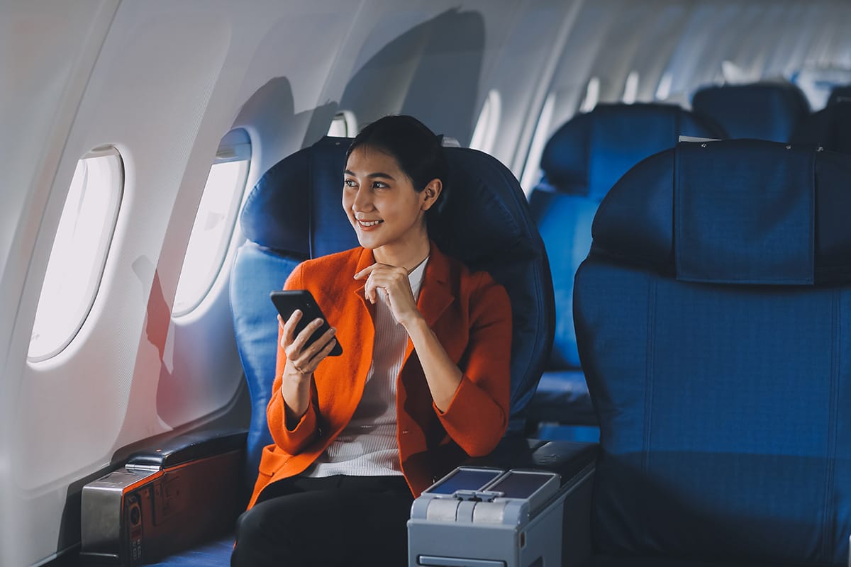 An image of a woman, smiling, sitting on an airliner