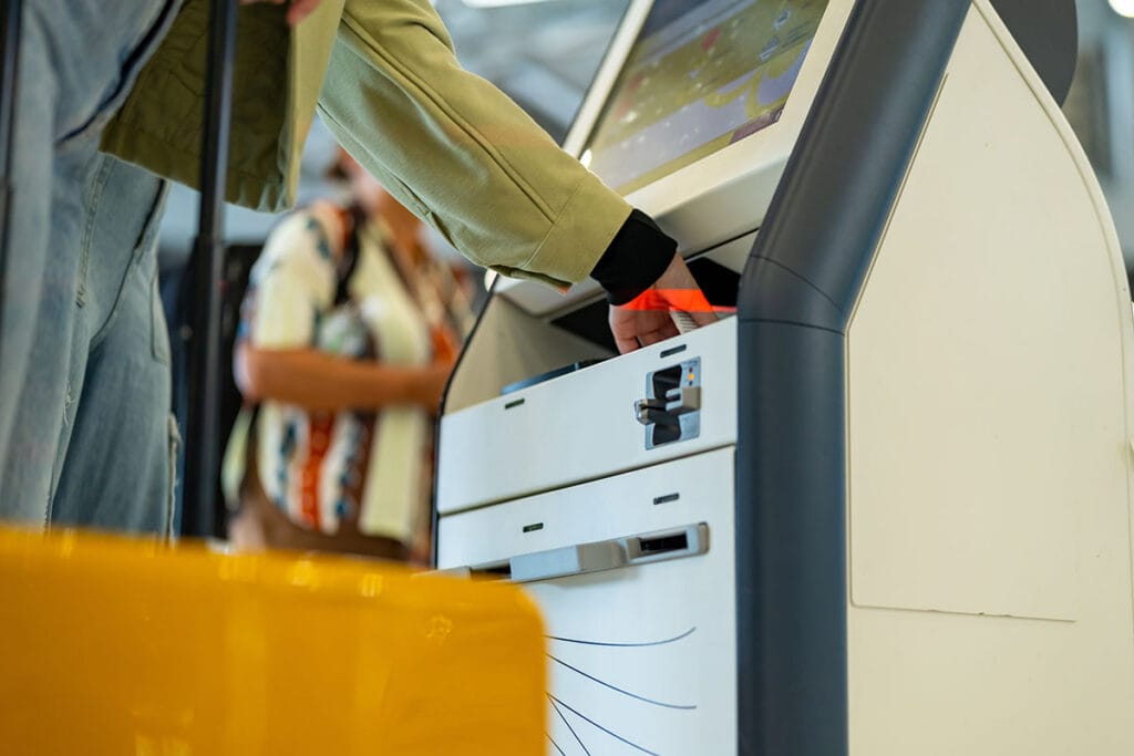 Een close-up van een reiziger die een selfservice ticketkiosk op een vliegveld gebruikt