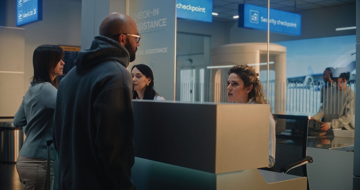 A man standing at an immigration desk talking to a woman